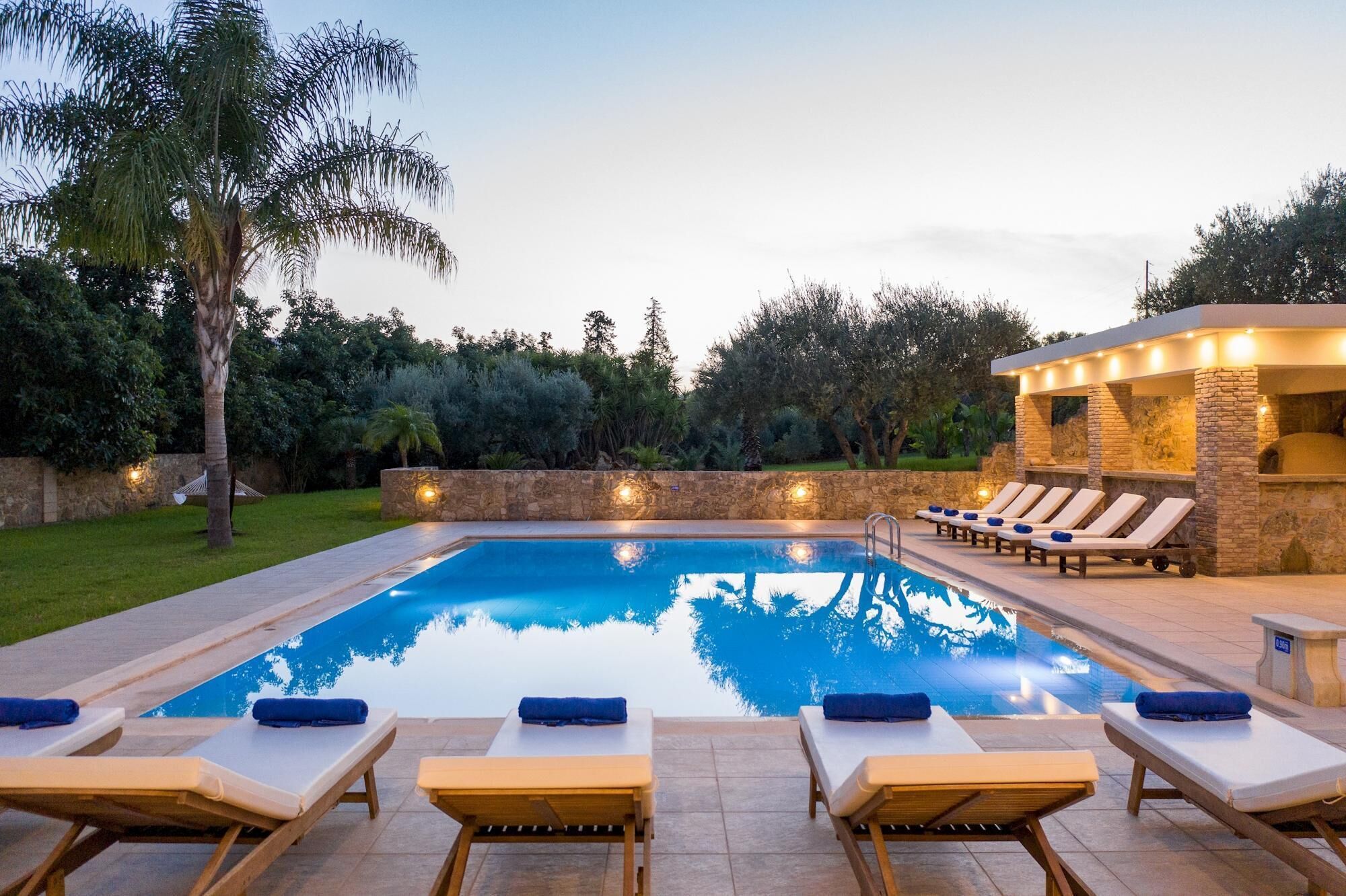 A swimming pool with lounge chairs and a stone structure with lights.