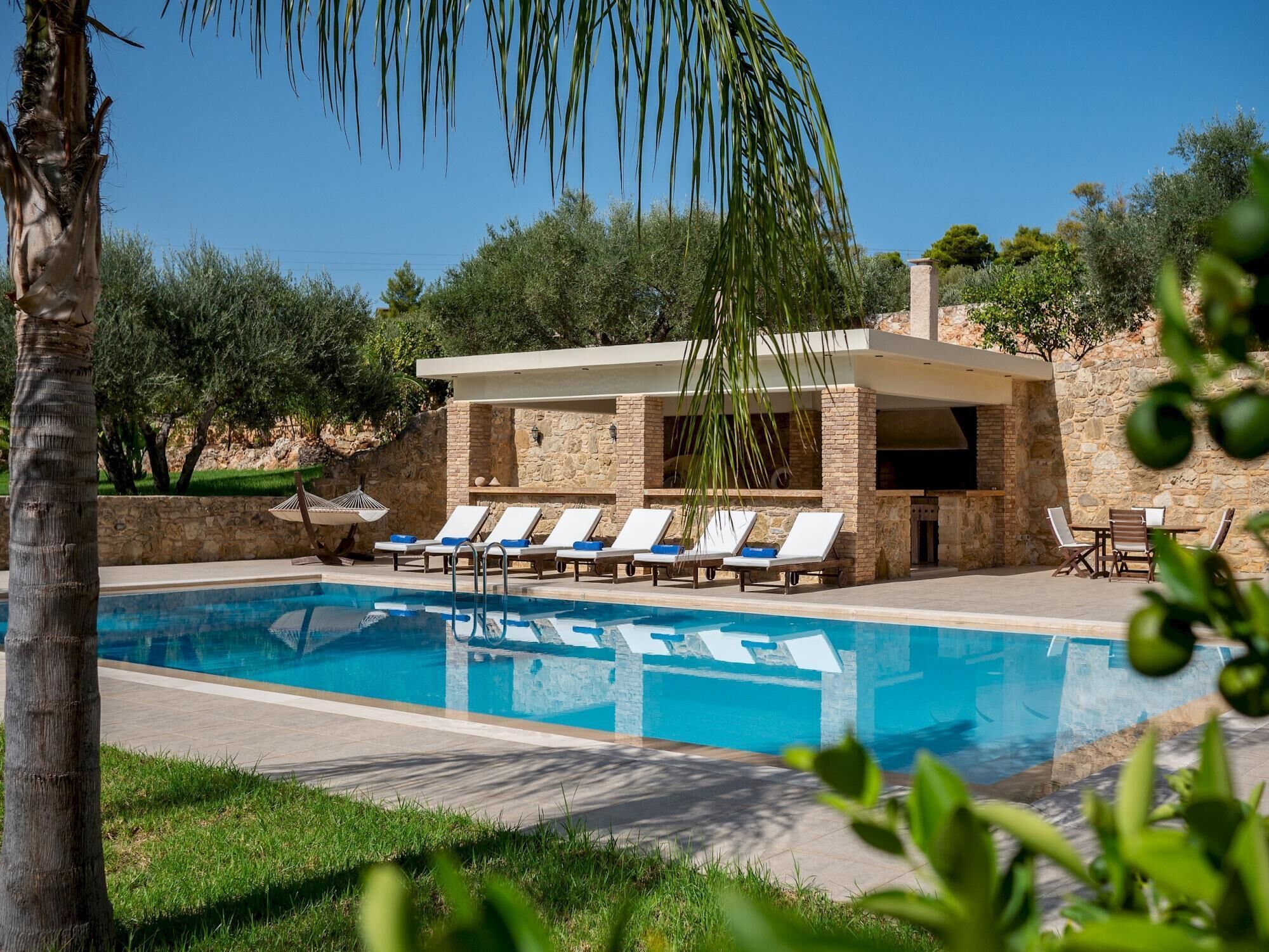 A pool area with lounge chairs and a stone building.