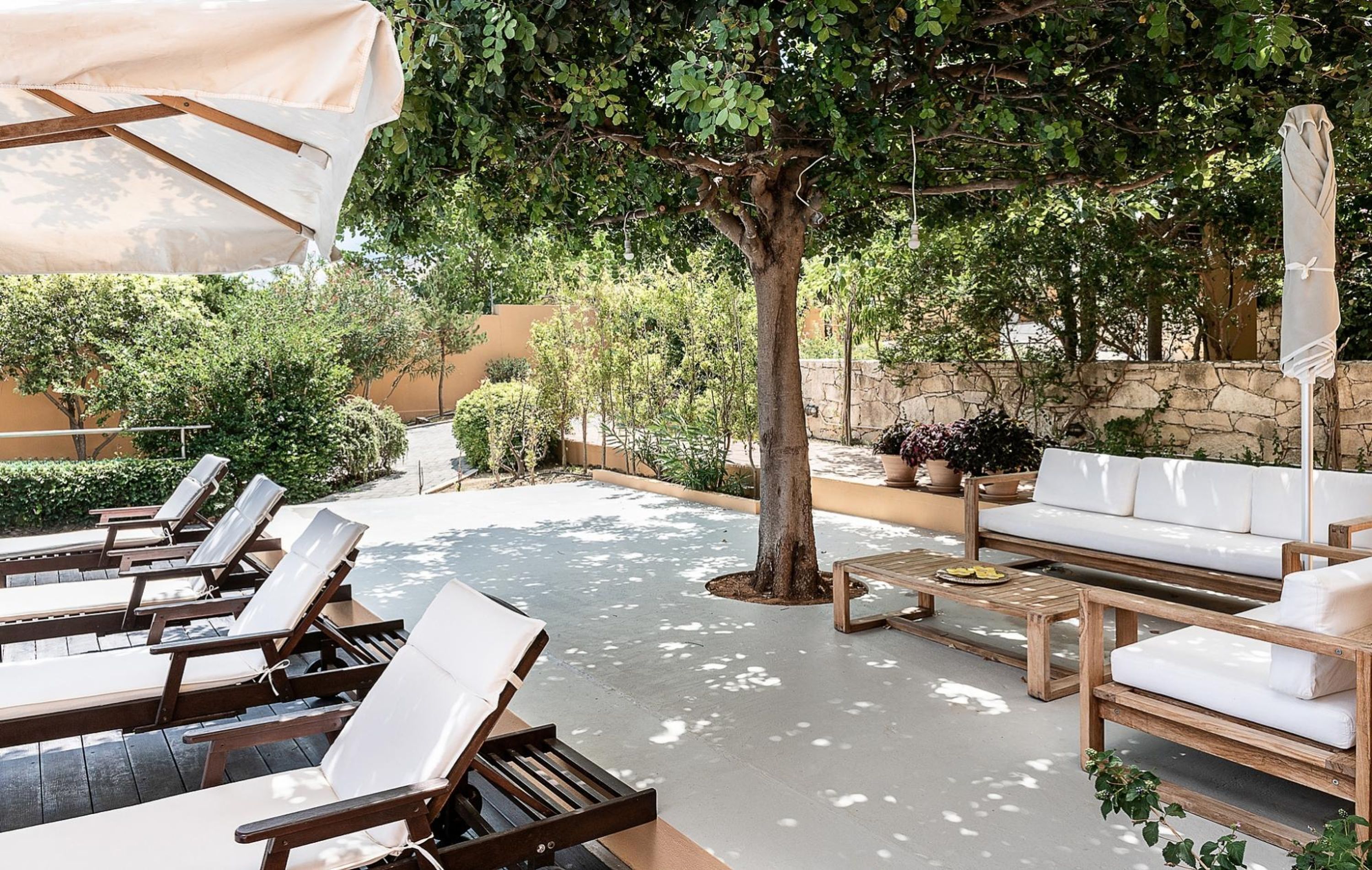 Eine Terrassengruppe im Freien mit Holzliegen, einer Couch und einem Tisch.