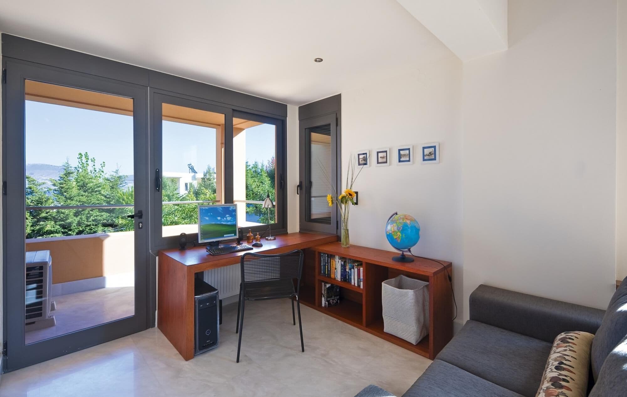 A modern living room with a large desk, a globe, and a bookshelf.