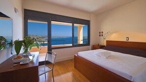 A bedroom with a large bed, a desk with a chair, a nightstand, and a view of the sea through a balcony door. - Chloe Seafront Villa (Chania)