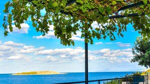An outdoor dining table with a view of the sea, a bottle of wine, and a bowl of fruit. - Chloe Seafront Villa (Chania)