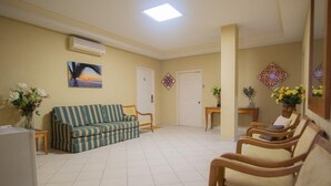 A reception area with a striped sofa, wooden chairs, a tiled floor, and a painting on the wall. - NEW Bay Harbor Studio 201 4 Persons (Oranjestad)