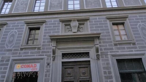 Un edificio histórico con una entrada destacada, un letrero que dice 'CONAD' y una puerta grande y ornamentada.