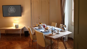 Un comedor con una mesa dispuesta para cuatro personas, una lámpara y un cuadro en la pared.