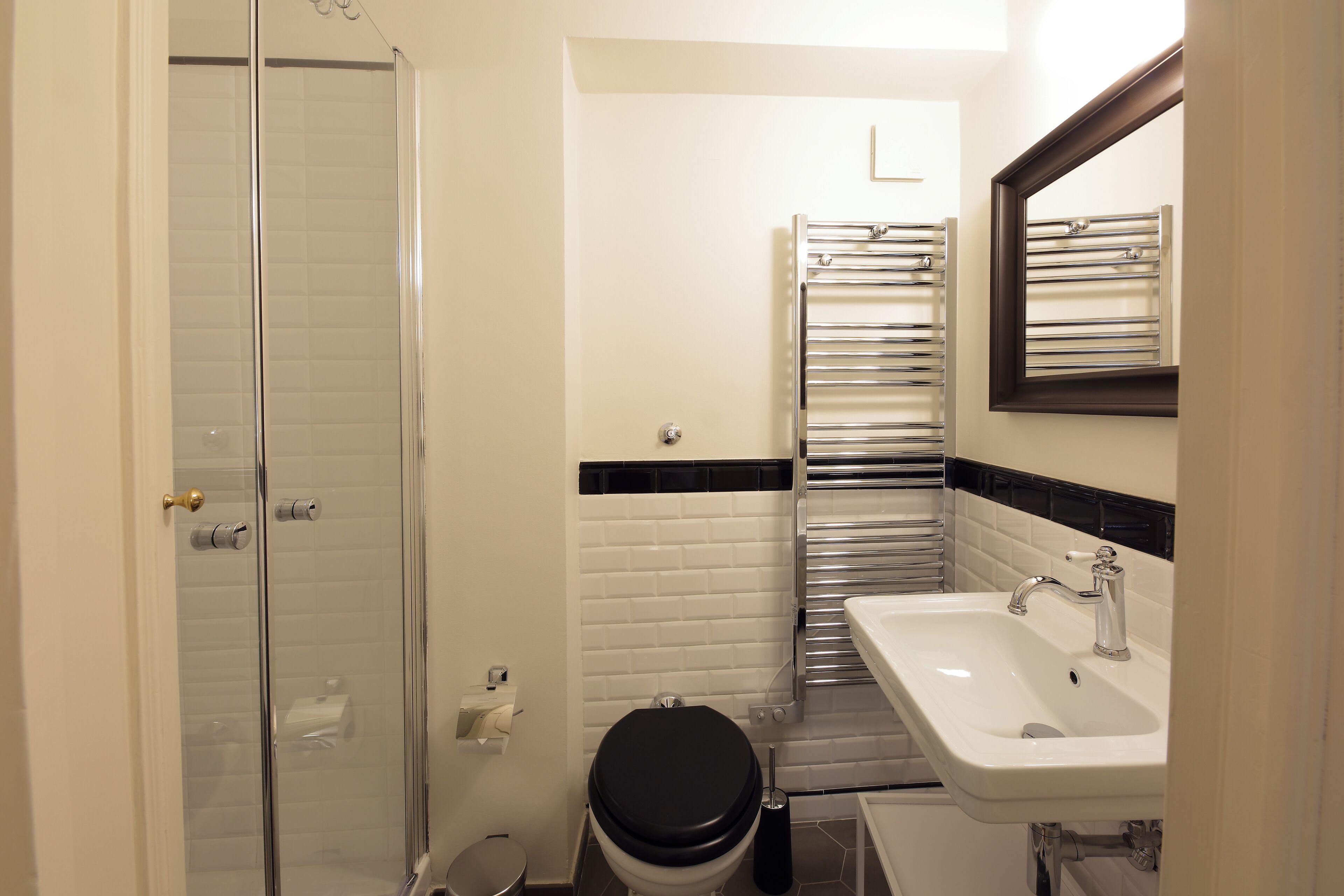 Ein Badezimmer mit Duschkabine aus Glas, Toilette, Waschbecken mit Spiegel und Handtuchhalter.