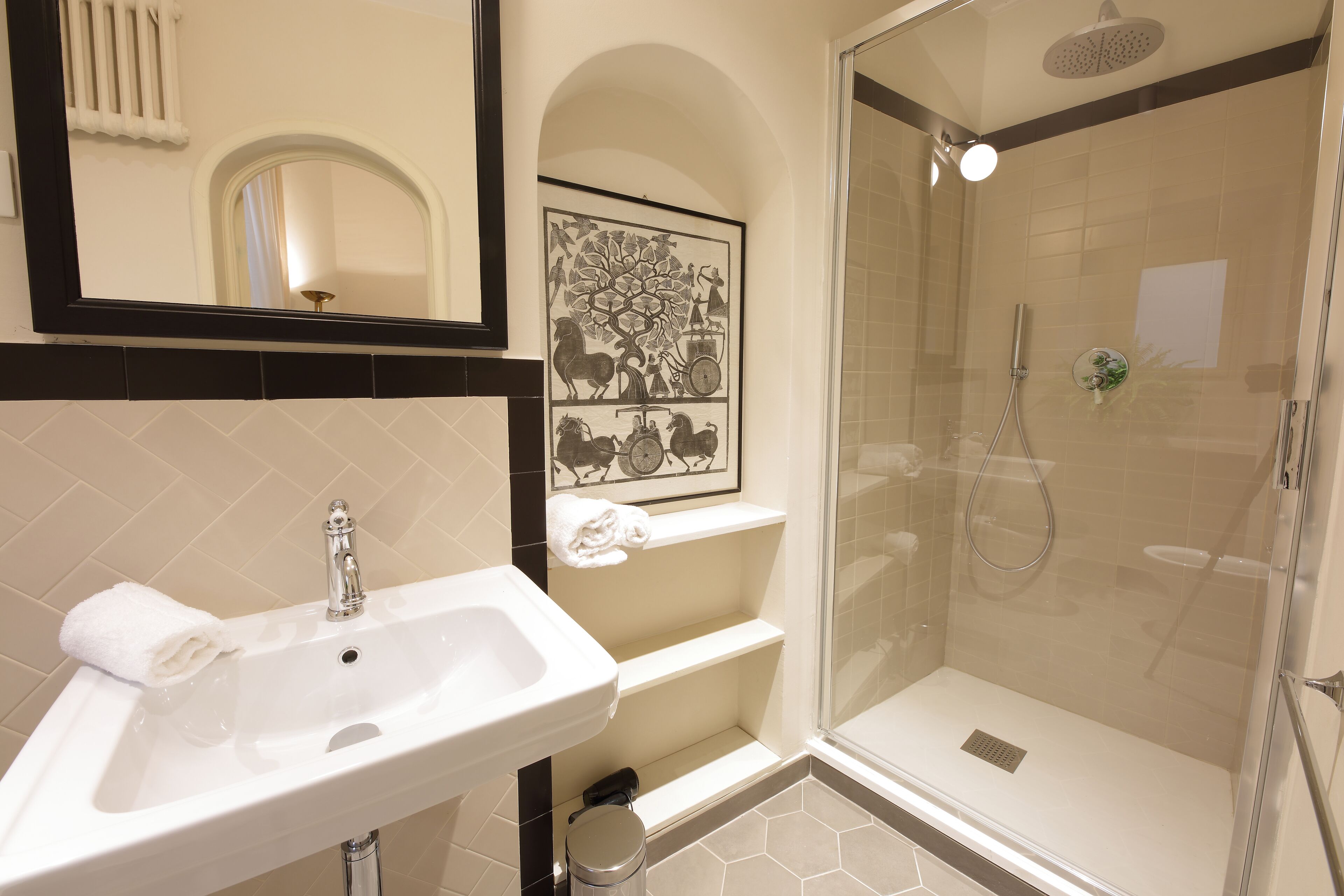 Ein Badezimmer mit Waschbecken, Spiegel, Dusche und einem gerahmten Kunstwerk über dem Waschbecken.