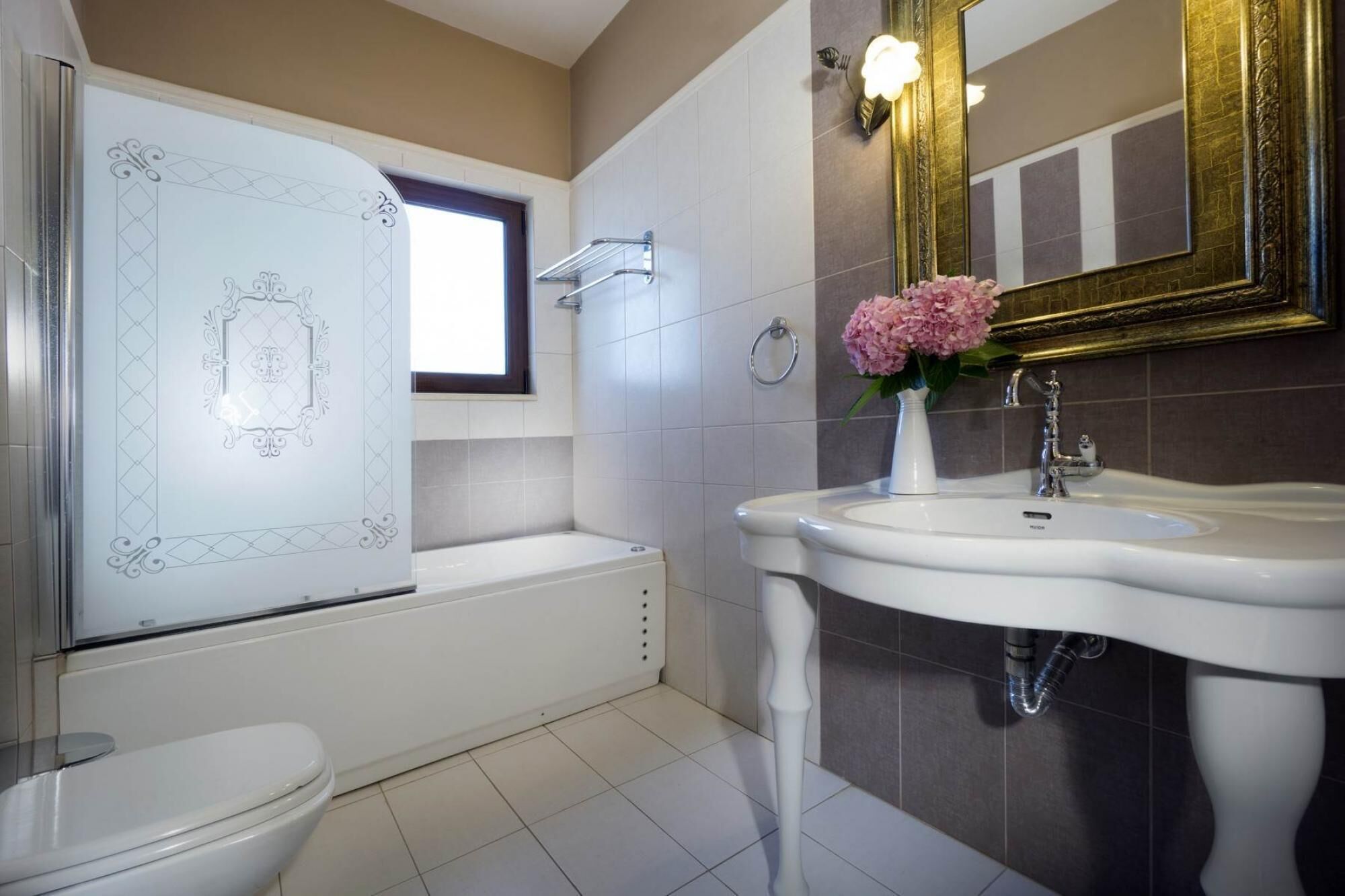 A bathroom with a white toilet, a bathtub, and a sink with a vase of flowers.