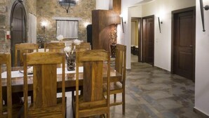 A dining area with a stone wall, wooden chairs, and a chandelier. - Nafsika Villa in Litsarda (Apokoronas)