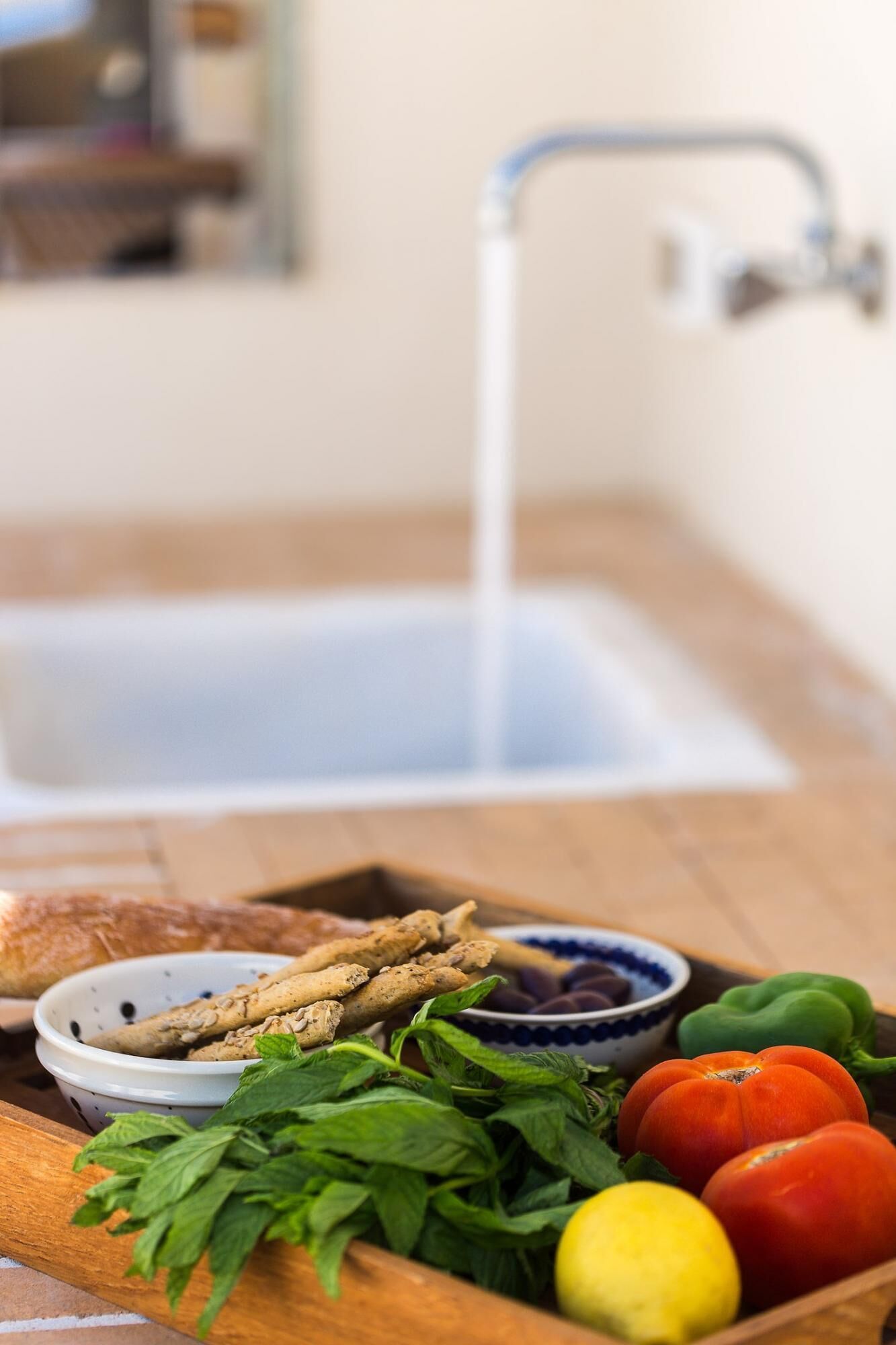 Una encimera de cocina con verduras frescas, hierbas y pan.