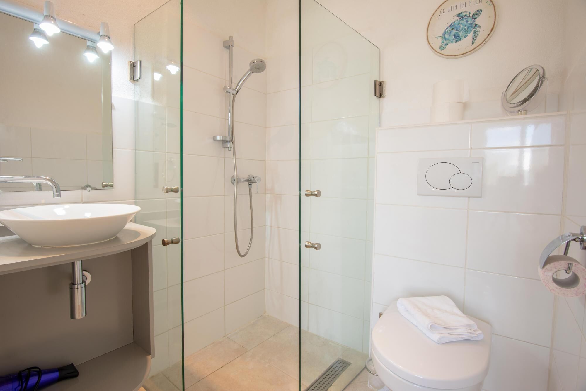 Ein modernes Badezimmer mit einer Glasdusche, einem weißen Waschbecken und einer Toilette.