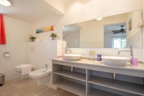 A modern bathroom with two sinks, a bidet, and a large mirror.