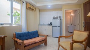 A compact living space with a sofa, a chair, a kitchenette, and a bathroom. - NEW Bay Harbor Studio 203 (Oranjestad)