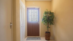 A hallway with a brown door, a potted plant, and a zebra-patterned mat. - NEW Bay Harbor Studio 203 (Oranjestad)