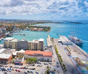 Un paisaje urbano costero con un puerto deportivo, edificios y un gran barco amarrado.