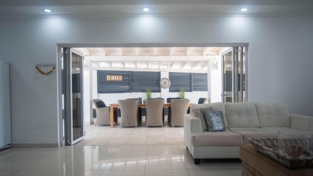 A modern living room with a sofa, a coffee table, and a dining area with a table and chairs. - Palm Beach 34 Suitable for 8 Persons 4 Bedrooms 4 Bathrooms (Noord)