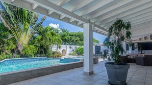 A covered outdoor area with a swimming pool, surrounded by lush greenery and a Buddha statue. - Palm Beach 34 Suitable for 8 Persons 4 Bedrooms 4 Bathrooms (Noord)