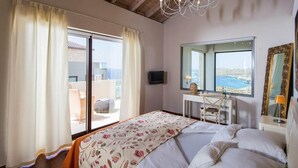 Ein Schlafzimmer mit einem Bett, einer Kristallleuchter, einem großen Fenster mit Aussicht und einem Spiegel.