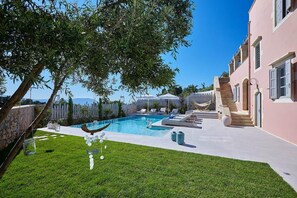 A swimming pool with lounge chairs, a staircase, and a pink building. - Villa Rouga in Xirosterni (Apokoronas)
