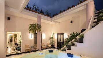 A modern indoor pool area with a checkered floor, lounge chairs, and a staircase leading to an upper level.