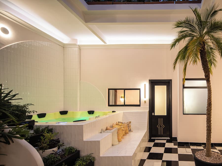 A modern bathroom with a large bathtub, a palm tree, and a checkered floor.