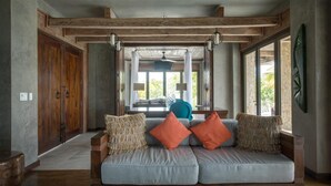 A modern living room with a sofa, orange cushions, and a view of the outdoors. - Gladden Caye Private Island Resort (Placencia)