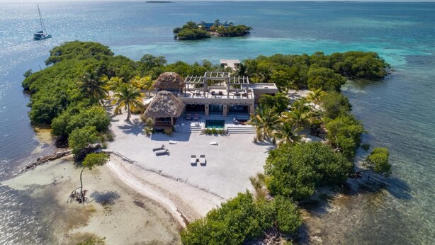 An aerial view of a tropical resort with a private beach, a pool, and lush greenery. - Gladden Caye Private Island Resort (Placencia)