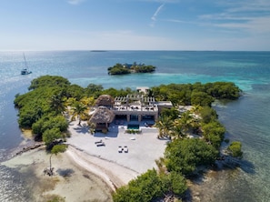 An aerial view of a tropical resort with a private beach, a pool, and lush greenery. - Gladden Caye Private Island Resort (Placencia)