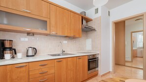 Una cocina moderna con armarios de madera, electrodomésticos de acero inoxidable y encimera blanca.