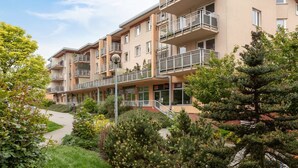Un edificio residencial de varios pisos con balcones, un camino pavimentado y vegetación circundante.