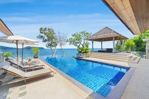 Ein Poolbereich mit Liegestühlen, Sonnenschirmen und einem Pavillon mit Blick auf ein Gewässer.