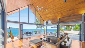 Ein modernes Wohnzimmer mit einer großen Glaswand, Holzboden und einem Deckenventilator.