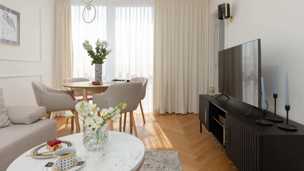 A modern living room with a sofa, dining table, and TV.