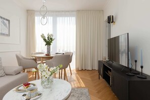 A modern living room with a sofa, dining table, and TV.