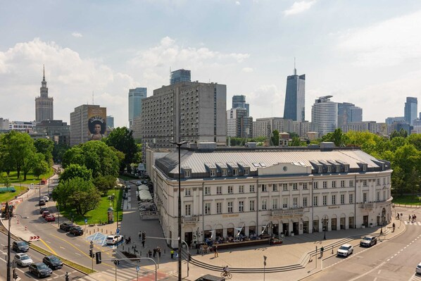 A large, historic building with a central courtyard, surrounded by modern high-rise buildings.