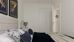 A bedroom with a bed, pillows, a bedside table with a lamp, and a door.