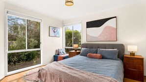 Een slaapkamer met een groot bed, twee nachtkastjes, een raam en kunst aan de muur.