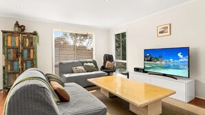 Een woonkamer met een bank, salontafel, televisie en een kast.