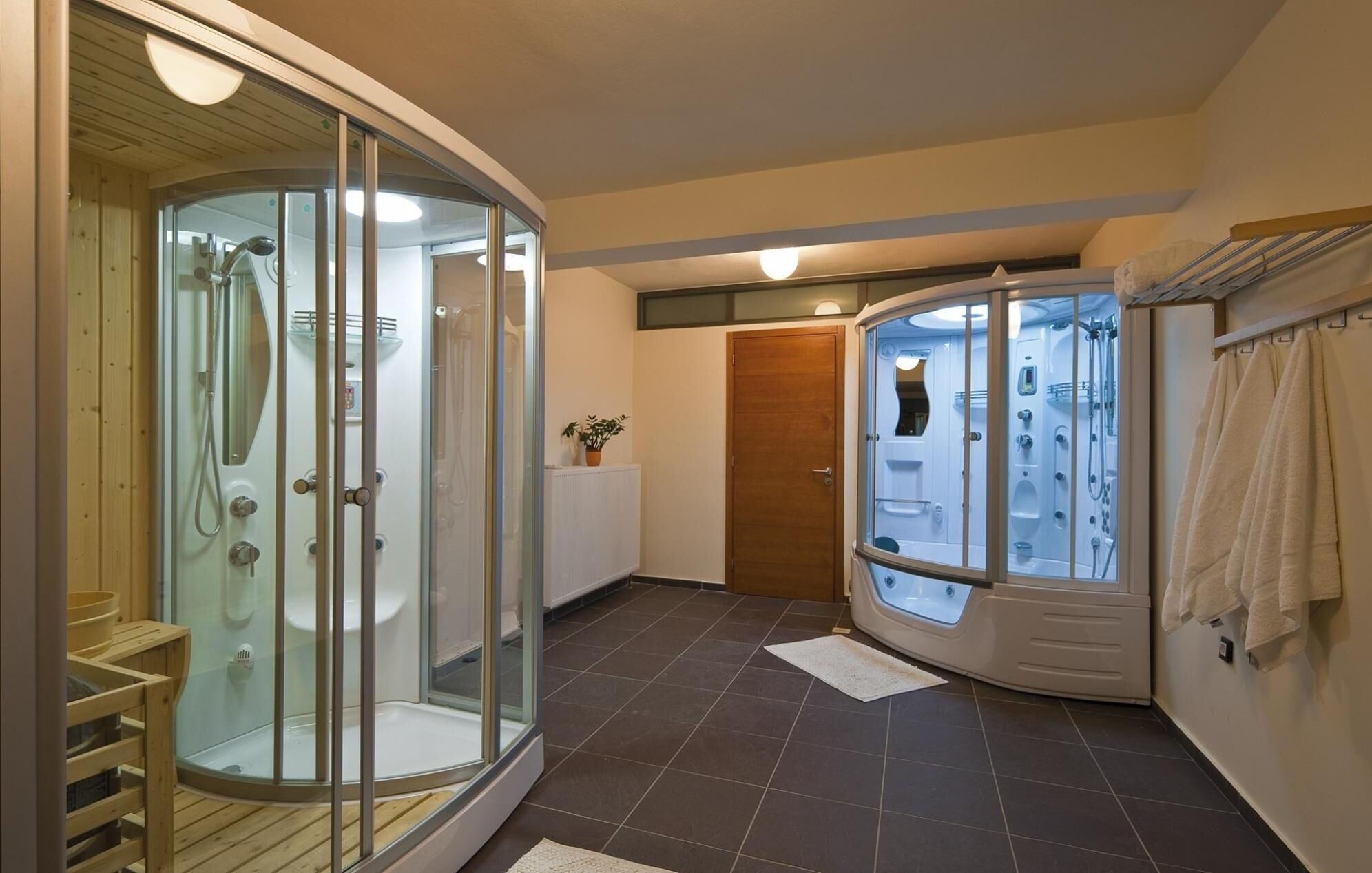 A modern bathroom with a glass-enclosed shower, a wooden bench, and a separate glass-enclosed jacuzzi area.