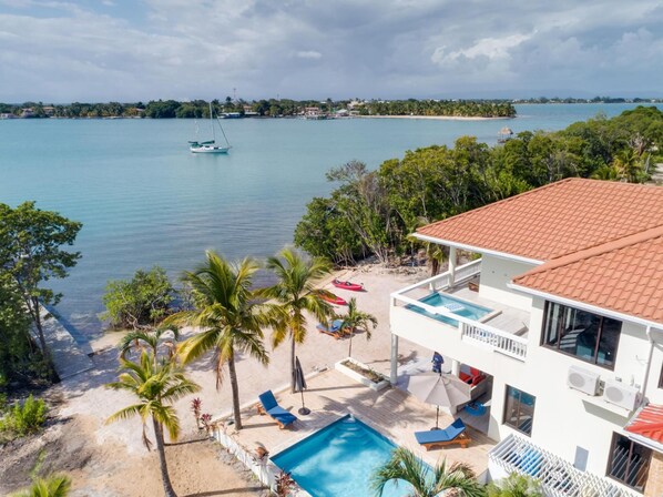 Um imóvel à beira-mar com piscina, espreguiçadeiras e vista para o mar.