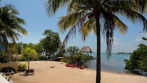 A beach with palm trees, a thatched-roof hut, and boats. - Villa Island Time Gecko (Placencia)