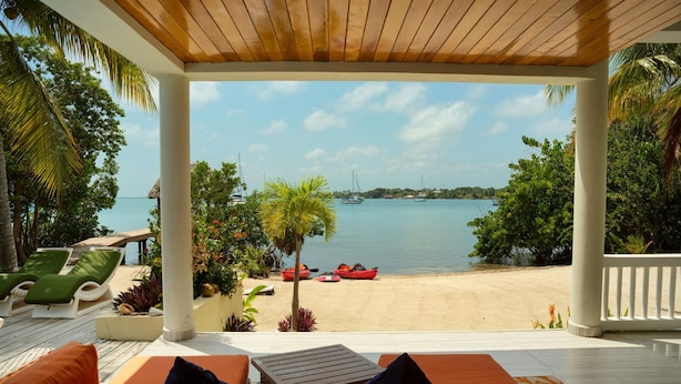 A covered outdoor seating area with a view of a beach and boats. - Villa Island Time Gecko (Placencia)