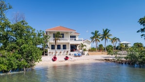 A two-story beachfront property with a balcony, clear water, and palm trees. - Villa Island Time Gecko (Placencia)