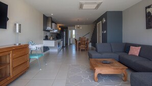 Una sala moderna con un sofá gris, una mesa de centro de madera, y un comedor con mesa y sillas.