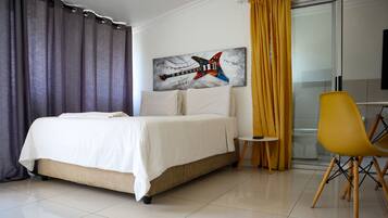 Habitación de hotel con cama, escritorio, silla y una obra de arte en la pared.