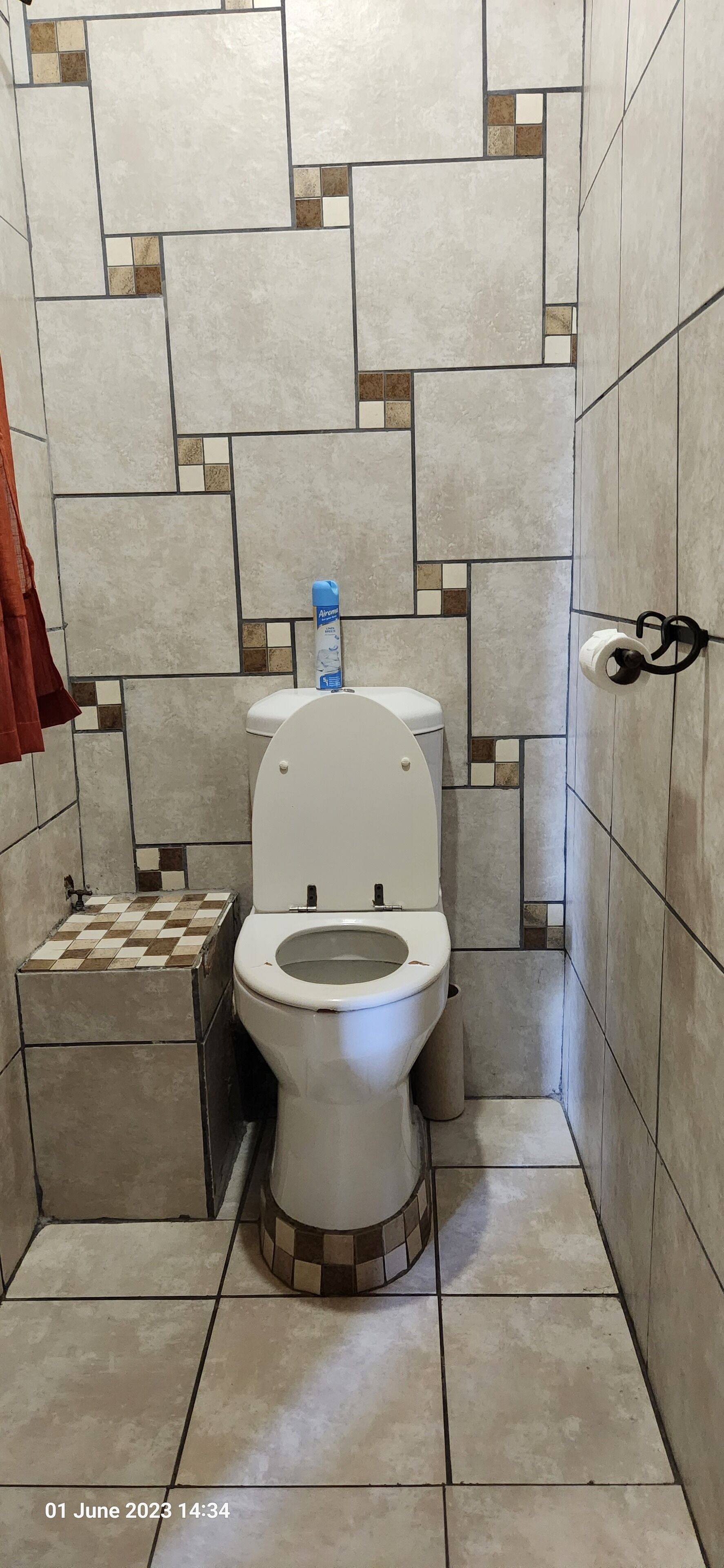 Une salle de bain avec des toilettes, une petite poubelle et un porte-serviettes.