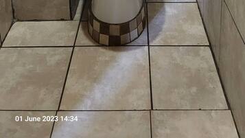 Une salle de bain avec des toilettes, une petite poubelle et un porte-serviettes.