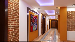 A hallway with brick walls, colorful artwork, recessed lighting, and a patterned floor. - MeroStay 179 Shree (Kathmandu)