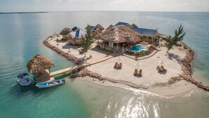 An overwater bungalow resort with thatched-roof structures, a swimming pool, and a dock with boats. - Exclusive Private Island With 360 Degree View of the Ocean (Placencia)