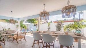A sunlit patio with a dining table, chairs, and lounge chairs. - NEW Cozy Casa in Oranjestad (Oranjestad)